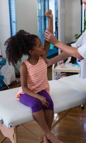 Physiotherapist giving hand massage to a girl in clinic